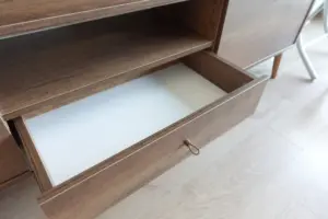 Open drawer in a manufactured wood media console with composite panel construction.