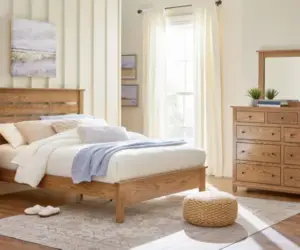 Solid wood bed and matching dresser in a bright, softly decorated bedroom.
