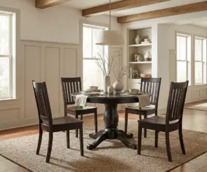 Round solid wood dining table with four matching chairs in a bright dining room.