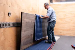 Mover wrapping a solid wood tabletop with a protective blanket while moving Amish furniture.